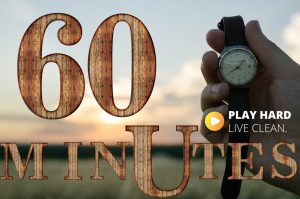 wooden letters "60 Minutes) hand holding watch - sunset background