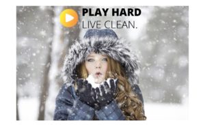 girl in coat- blowing snow from her hands outside